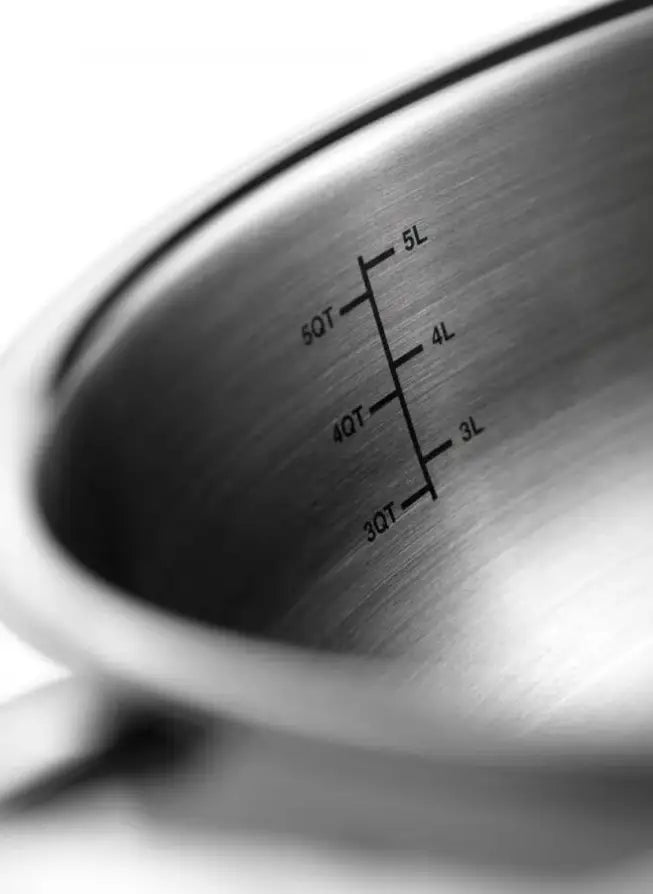 Close-up of the inside of a stainless steel pot or pan showing printed liquid measurement markings in liters and ounces.